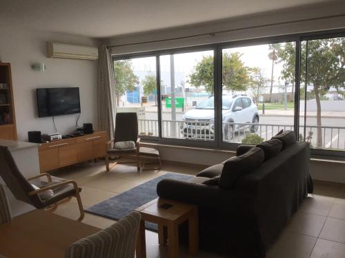 a living room with a couch and a large window at Rainha Juliana in Fuzeta