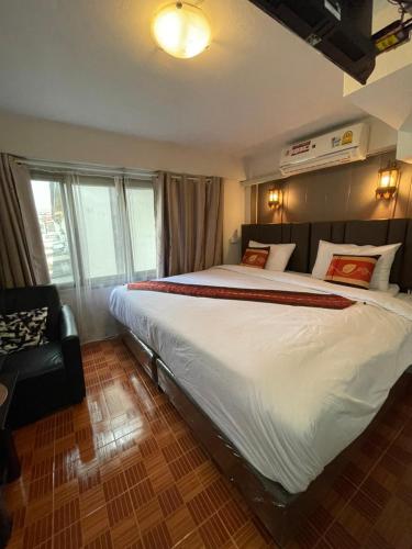 a bedroom with a large bed and a chair at Acozyposhtel in Bangkok