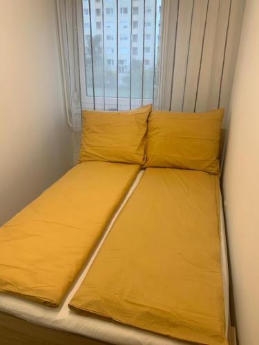 a bed in a room with yellow sheets and a window at Szabó Apartman in Miskolc