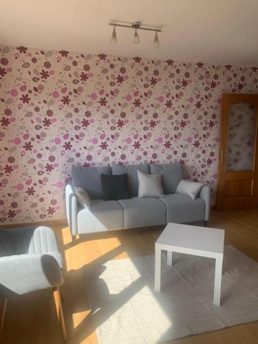 a living room with a couch and flowers on the wall at Mirador de Valcayo in Riaño