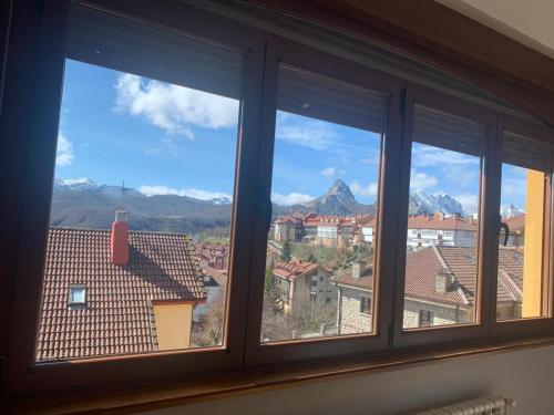 a window with a view of mountains and buildings at Mirador de Valcayo in Riaño