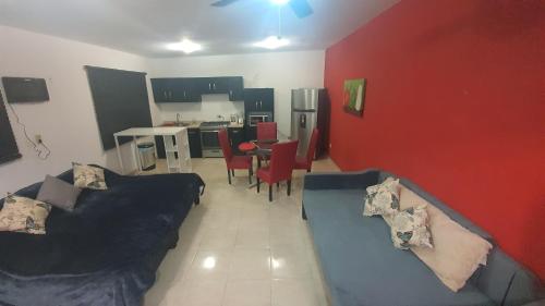a living room with a black couch and a red wall at DEPARTAMENTO NUEVO Y CENTRICO EN MITRAS NORTE in Monterrey