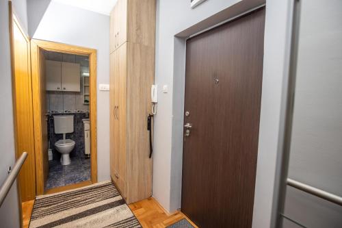 a bathroom with a toilet and a wooden door at Apartment Sole in Cetinje