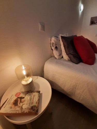 um pequeno quarto com uma cama e uma mesa com um livro em Family House em Vila do Bispo