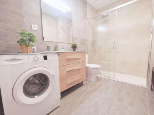 uma máquina de lavar roupa branca na casa de banho com um chuveiro em Casa Kimo Platja em Vilanova i la Geltrú