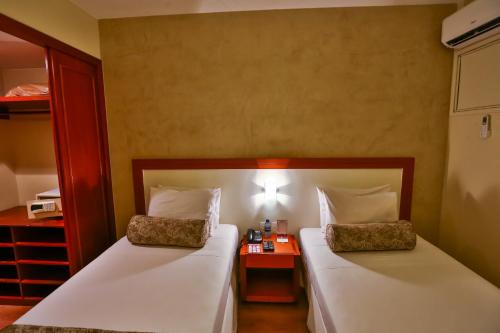 a bedroom with two beds and a night stand at Metropolitan Hotel Brasília in Brasilia