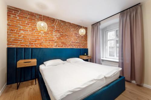 ein Schlafzimmer mit einem Bett und einer Ziegelwand in der Unterkunft Coffee Apartments, MyWeek in Kłodzko