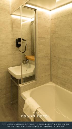 a bathroom with a bath tub and a sink at Grand Hôtel Bénodet Abbatiale Riviera Bretonne in Bénodet