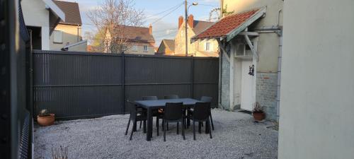 una mesa y sillas en un patio trasero con una valla en Gîte des brebis, en Warmeriville