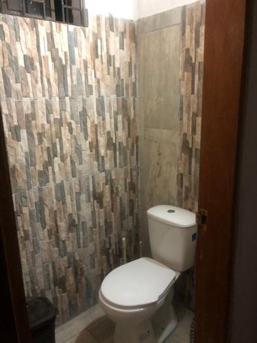 a bathroom with a toilet and a tile wall at Jamadis in Tolú
