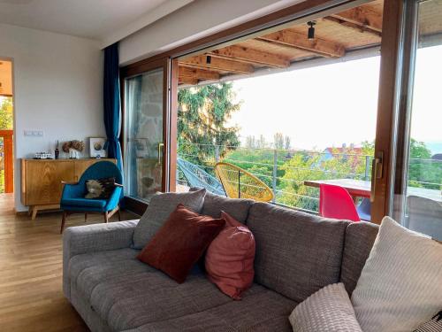 a living room with a couch and a large window at Hello Balaton in Alsóörs