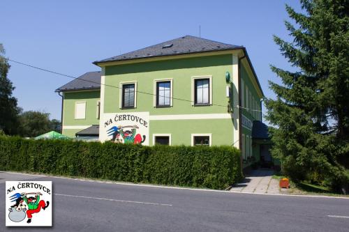 a green house with a sign in front of it at Penzion na Čertovce in Dolní Orlice