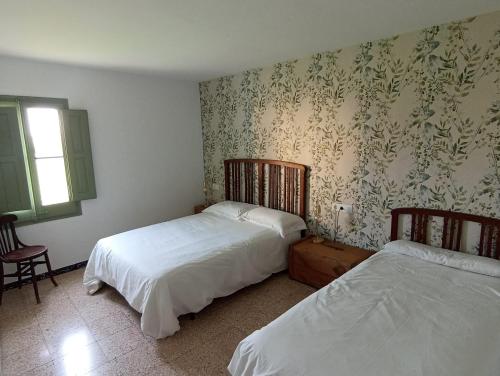 a bedroom with two beds and a wall with wallpaper at Cal Pigat in Miravet