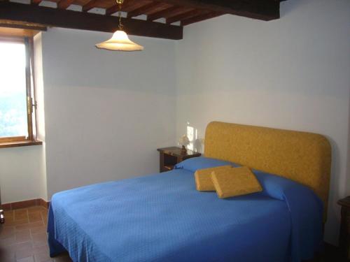 een slaapkamer met een blauw bed en een geel kussen bij casa Dany in Bagni di Lucca