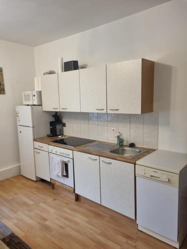 a kitchen with white cabinets and a sink at FeWo Teusch Top4 in Arnoldstein