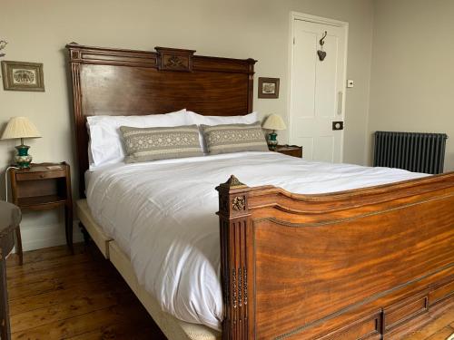 um quarto com uma grande cama de madeira com lençóis brancos em Gloucester House em Hastings