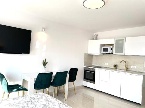 a kitchen with white cabinets and a table and chairs at Apartment Vila ** in Stinica