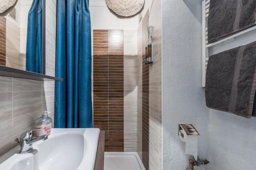 a bathroom with a sink and a blue shower curtain at Studio "Les Roches blanches" - Vue mer & Vignes in Banyuls-sur-Mer