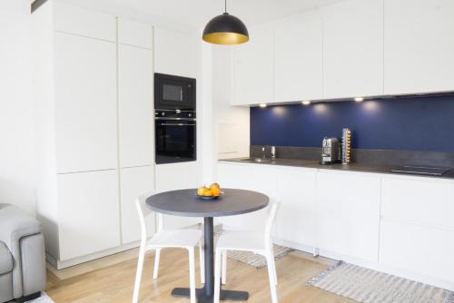 a kitchen with a table and two white chairs at EXIGEHOME-Appartement de standing en plein centre ville in Maisons-Laffitte