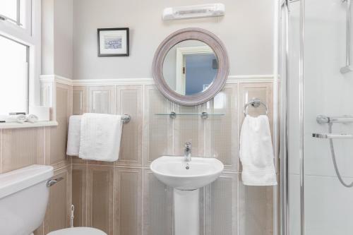 a white bathroom with a sink and a mirror at The Lighthouse in Dingle