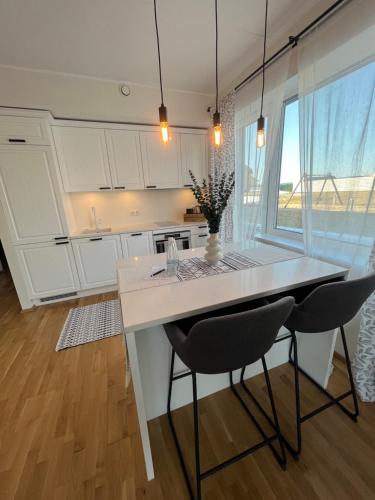 a kitchen with white cabinets and a table and two chairs at Suburb stay by Overnight.ee in Petrikyula