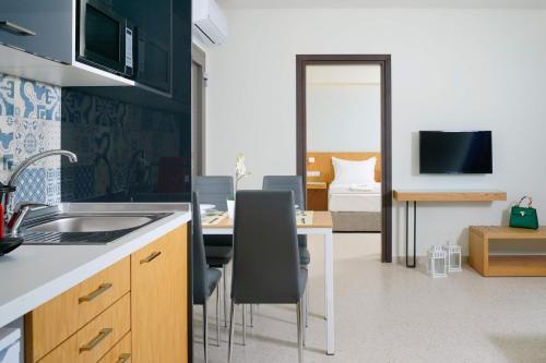 a kitchen with a sink and a table with chairs at Encanto Village -Apartments in Potos
