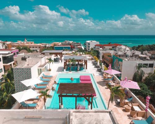 una vista aérea de una piscina con sombrillas y el océano en Hotel The Palm en Playa del Carmen