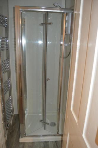 una doccia con una porta in vetro in un bagno di Carnegie Holiday Cottage a Dunfermline