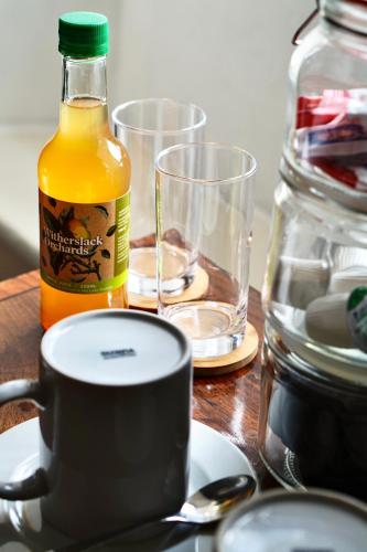 a table with a cup of orange juice and two glasses at Derby Arms Witherslack in Grange Over Sands