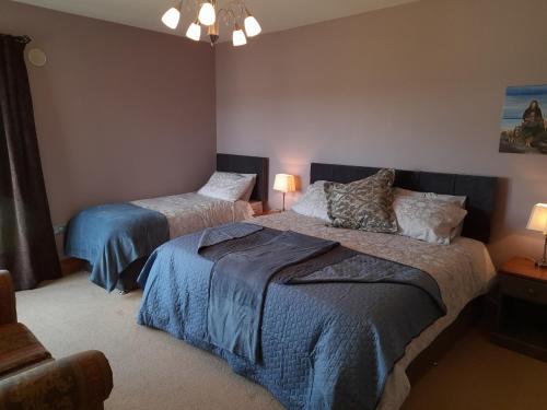 a bedroom with two beds and a chair and lamps at Oak Tree Lane Country B and B in Bridgetown