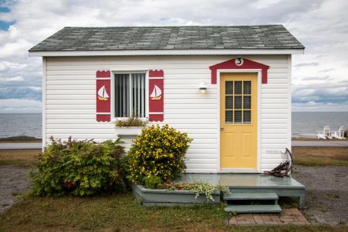 a small house with a yellow door in front of the ocean at Les Cabines du Phare in Rimouski