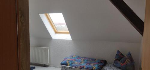 an attic room with a window and a ottoman at Pension Bärbel in Bernburg