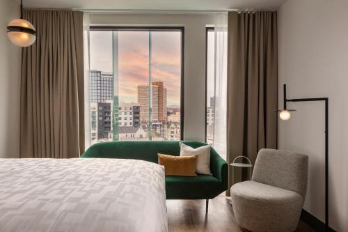 a hotel room with a bed and a chair and a window at Kissel Uptown Oakland, in the Unbound Collection by Hyatt in Oakland