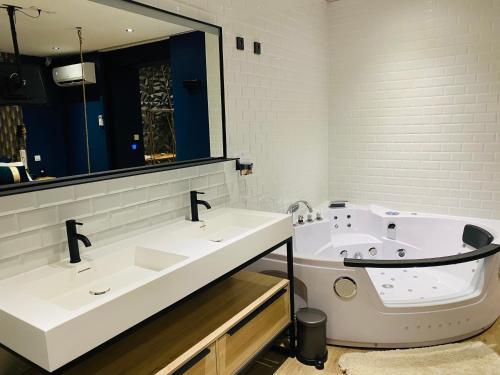 a bathroom with two sinks and a bath tub at Capsule Temps suspendu - balnéo, home cinema & billard in Valenciennes