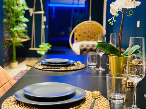 a table with blue plates and glasses on it at Capsule Temps suspendu - balnéo, home cinema & billard in Valenciennes