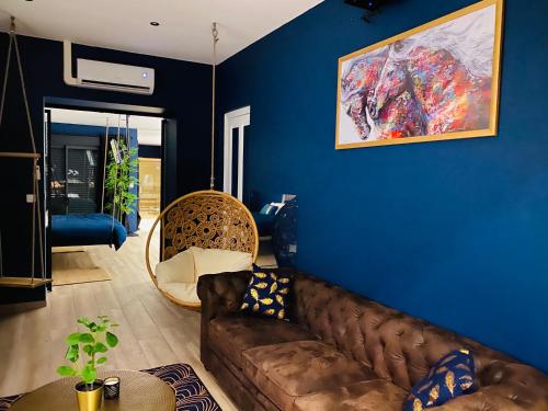 a living room with a brown couch and a blue wall at Capsule Temps suspendu - balnéo, home cinema & billard in Valenciennes
