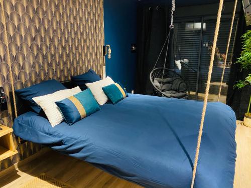 a swing bed in a room with blue and white pillows at Capsule Temps suspendu - balnéo, home cinema & billard in Valenciennes