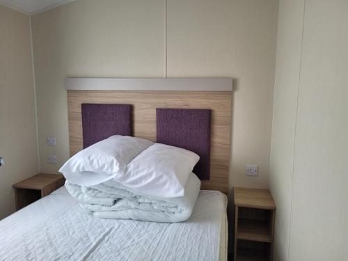 een bed met witte lakens en kussens erop bij 10 Berth on Seaview (Linwood) in Ingoldmells
