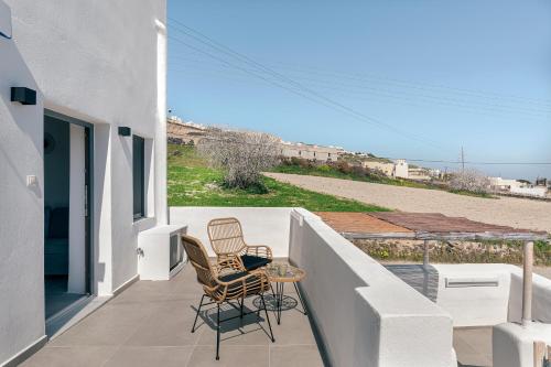 twee stoelen en een tafel op het balkon van een huis bij Episkopi Estate Cycladic Villas in Éxo Goniá
