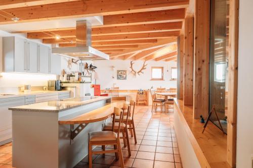 an open kitchen with wooden ceilings and wooden stools at Reiterhof Berggut Gaicht in Nesselwängle