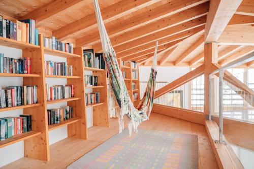 a hammock hanging in a room with bookshelves at Reiterhof Berggut Gaicht in Nesselwängle