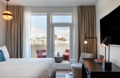 ein Hotelzimmer mit einem Bett, einem Schreibtisch und einem Fenster in der Unterkunft Kissel Uptown Oakland, in the Unbound Collection by Hyatt in Oakland