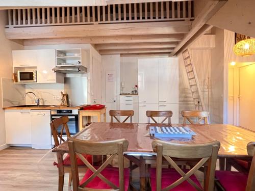 une cuisine et une salle à manger avec une table et des chaises en bois dans l'établissement Place de la mairie T2 type loft 70m2 terrasse 35m2, à Cauterets