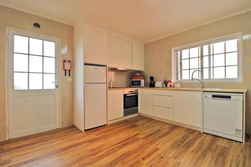 a kitchen with white cabinets and a wooden floor at Casa das Vinhas in Mosteiros
