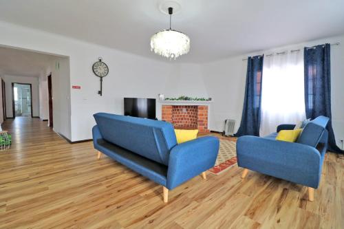a living room with two blue chairs and a fireplace at Casa das Vinhas in Mosteiros