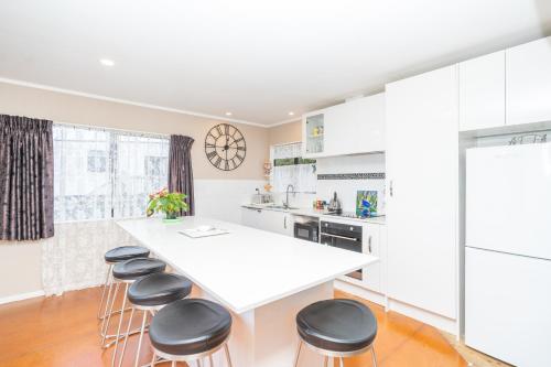 a kitchen with a white counter top and stools at Family Home on Robert St in Raglan