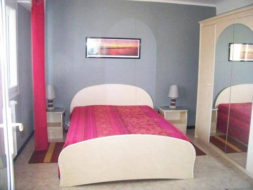 a bedroom with a bed with a red and white bedspread at Rez-de-jardin 50 m² entre Biarritz et Capbreton in Ondres