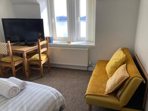 a bedroom with a couch and a table and a television at Port House in Gairloch