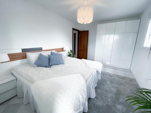 a white bedroom with a large bed with blue pillows at La Zenia Beach House in Alicante