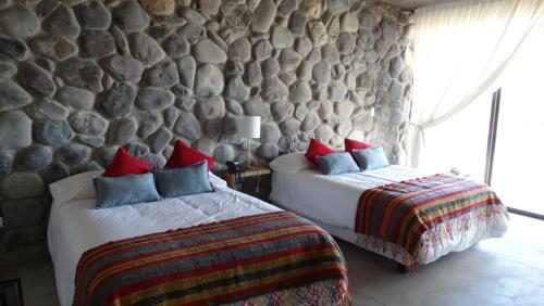 a bedroom with two beds and a stone wall at Casa de Huéspedes La Azul in Los Árboles